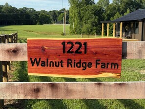 A wooden sign with the number 1221 and the text 'Walnut Ridge Farm' on a wooden fence.