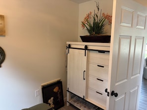 A white cabinet with black handles and a plant on top.