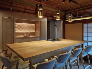 A modern kitchen with a large island, bar stools, pendant lighting, and a view of the dining area.