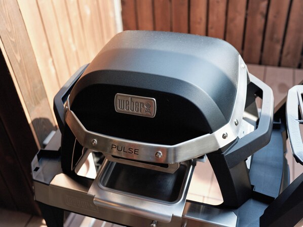 Una parrilla Weber Pulse con acabado negro y un mango de acero inoxidable.