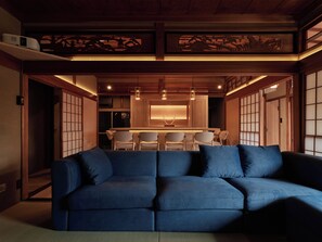 A traditional Japanese interior with a blue sofa, wooden sliding doors, and a dining area with chairs.