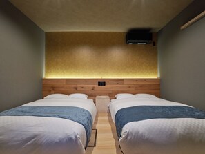 A hotel room with two beds, a wooden headboard, a wall-mounted air conditioner, and a lighted wall.