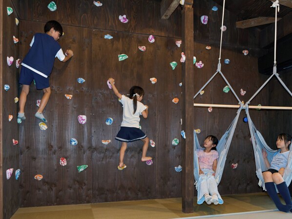 A wooden climbing wall with colorful holds and a rope system. - KONJAKUSO Nara Kitamachi MANAKA Spa (Narashi)