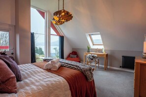 Une chambre à coucher comprenant un lit, un bureau, une chaise, un radiateur et une lucarne.