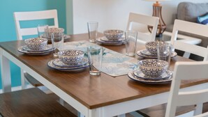 Een eettafel gedekt met blauwe kommetjes, glazen en een placemat.