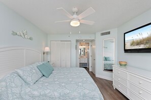 A bedroom with a bed, a ceiling fan, a dresser, and a bathroom visible through an open door. - Amazing OceanView•14th-Fl• Spacious 3BR •Fireplace •Pool• Sleeps 10 (Myrtle Beach)
