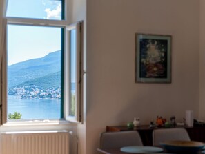 Ein Zimmer mit Blick auf einen See und einen Berg, inklusive Heizkörper, Tisch und einem gerahmten Bild an der Wand.