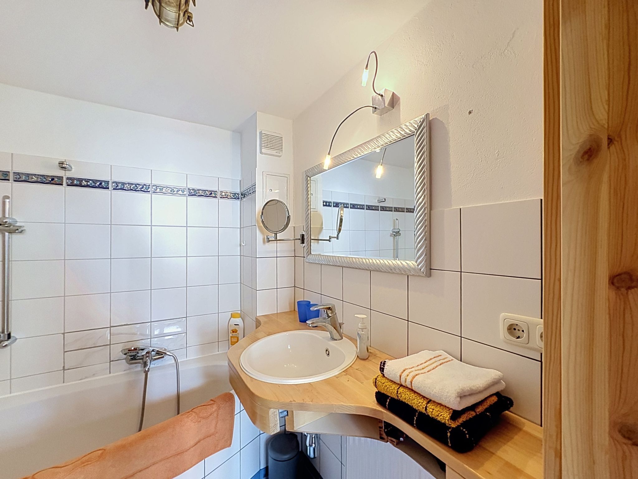 Un baño con lavamanos, espejo, toallero y ducha.