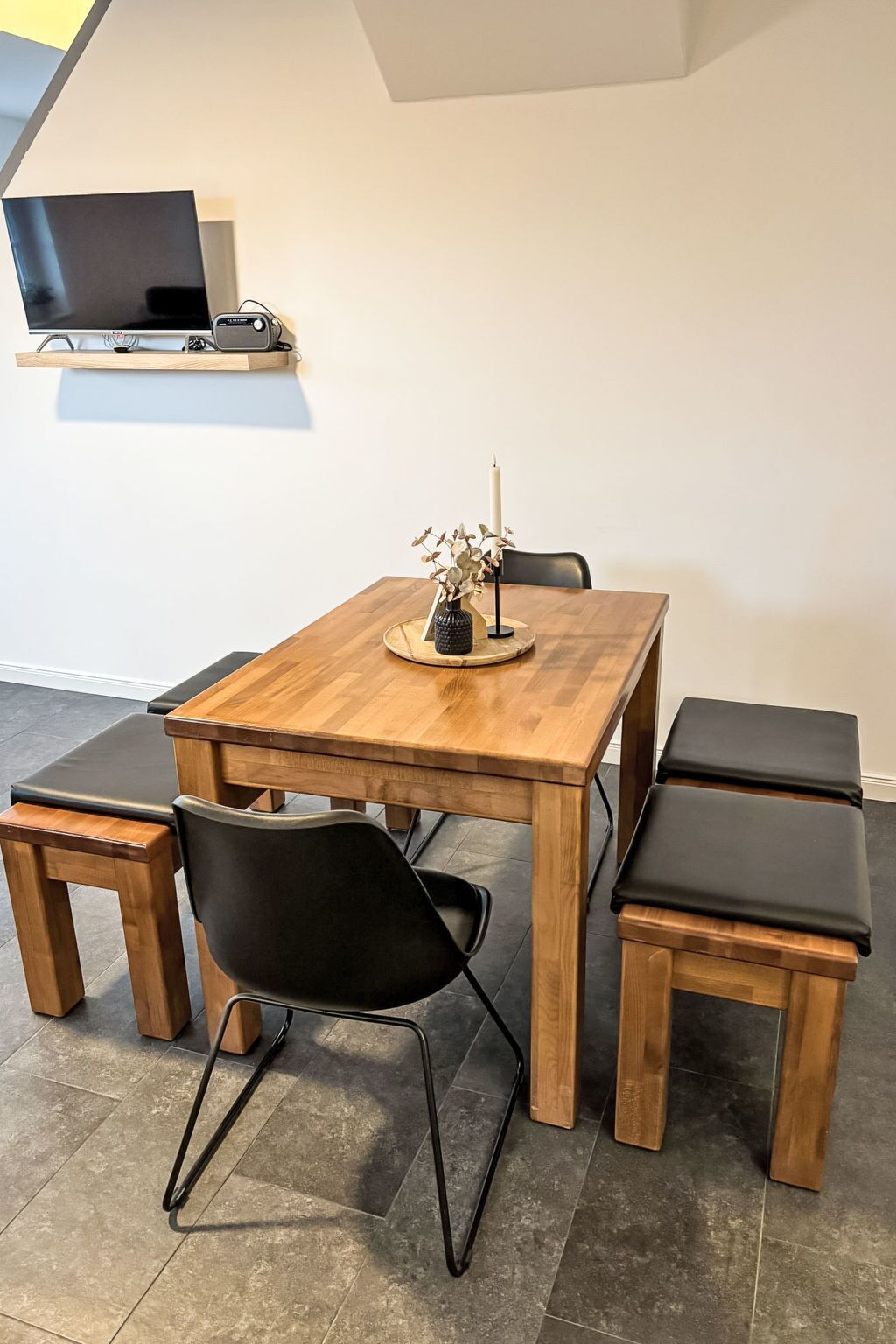 Un comedor con una mesa de madera, sillas negras y un centro de mesa con vela.