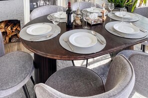 Una mesa de comedor con platos, cubiertos y vasos, rodeada de sillas tapizadas.