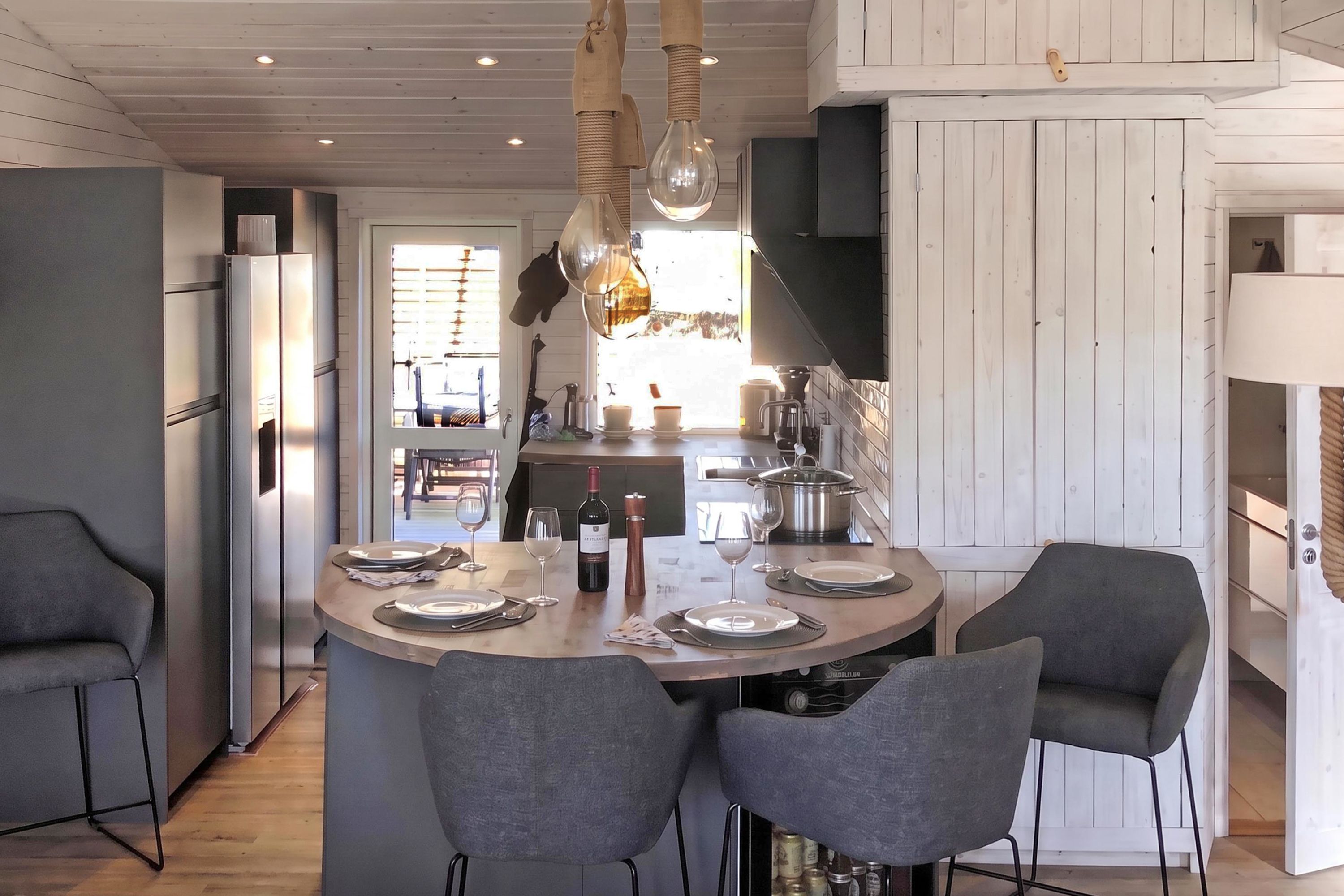 A modern kitchen with a central island, two grey chairs, and a hanging light fixture.