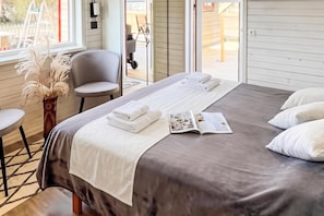 Una habitación de hotel con cama, una silla, un ventanal y una revista sobre la cama.