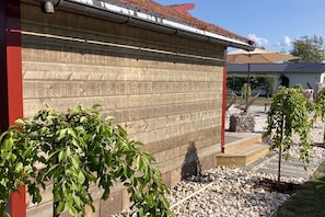 A wooden building with a metal roof, surrounded by gravel and small trees. - Skummeslöv Beach Home B, Skummeslövstrand, Sweden (Skummeslövstrand)