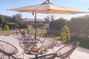 An outdoor patio with wicker chairs, a table with pastries, and a large umbrella. - Skummeslöv Beach Home B, Skummeslövstrand, Sweden (Skummeslövstrand)