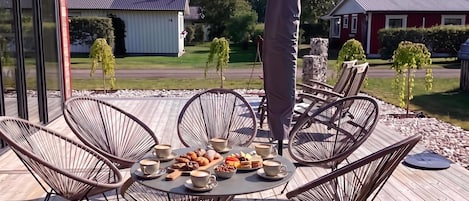 En uteservering med ett runt bord, stolar och ett varierat utbud av mat och dryck.