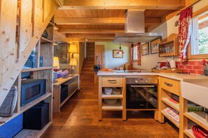 Ein Holzinnenraum mit Küchenzeile, darunter eine Mikrowelle, ein Backofen und Holzschränke.