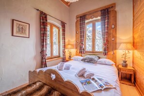 Ein gemütliches Schlafzimmer mit einem hölzernen Bett, zwei Nachttischlampen und einem Fenster mit Vorhängen.