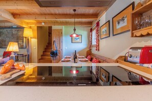 Eine Küche mit Kochinsel, Holzboden und einem Essbereich mit Treppe.