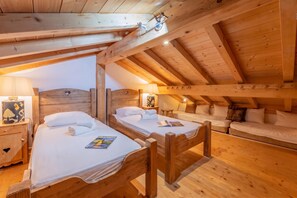 Ein gemütliches Holzhaus mit zwei Einzelbetten, einem Sofa und einem kleinen Tisch.