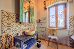 A bathroom with a wooden sink, a mirror, a window with curtains, and a patterned wall. - Le Hameau Du Buet - Ski Nature Views, Vallorcine (Argentiere), France (Vallorcine (Argentiere))