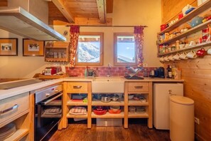 Eine kleine Küche mit Holzausstattung, einem eingebauten Backofen und einem Kühlschrank.