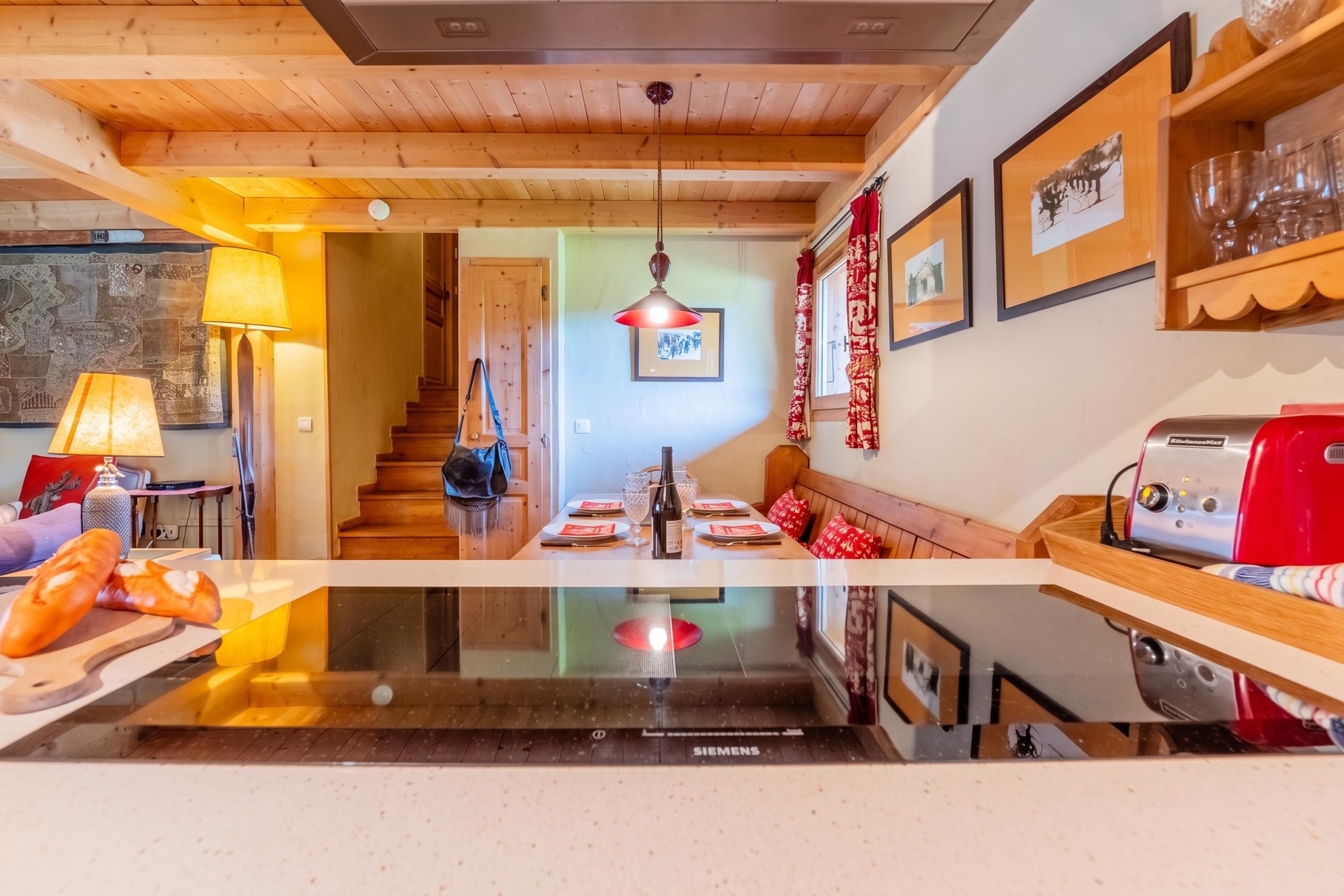 A modern kitchen with a central island, wooden ceiling, and a dining area with a bench.