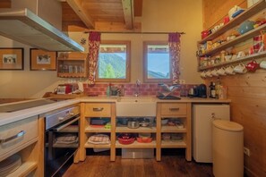 Eine kleine Küche mit Holzschränken, einem Einbauofen, einem Spülbecken und einem kleinen Kühlschrank.