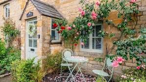 A stone building with a small garden, a bench, and a table.