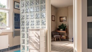 Ein Zimmer mit einem großen Fenster, einem Heizkörper, einer blauen Matte, einem Stuhl, einer Pflanze und einem Regal mit Büchern.