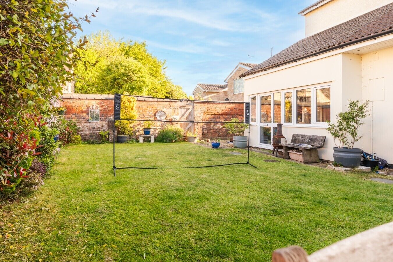 Ein Garten mit Trampolin, Grillplatz und einer Backsteinmauer.