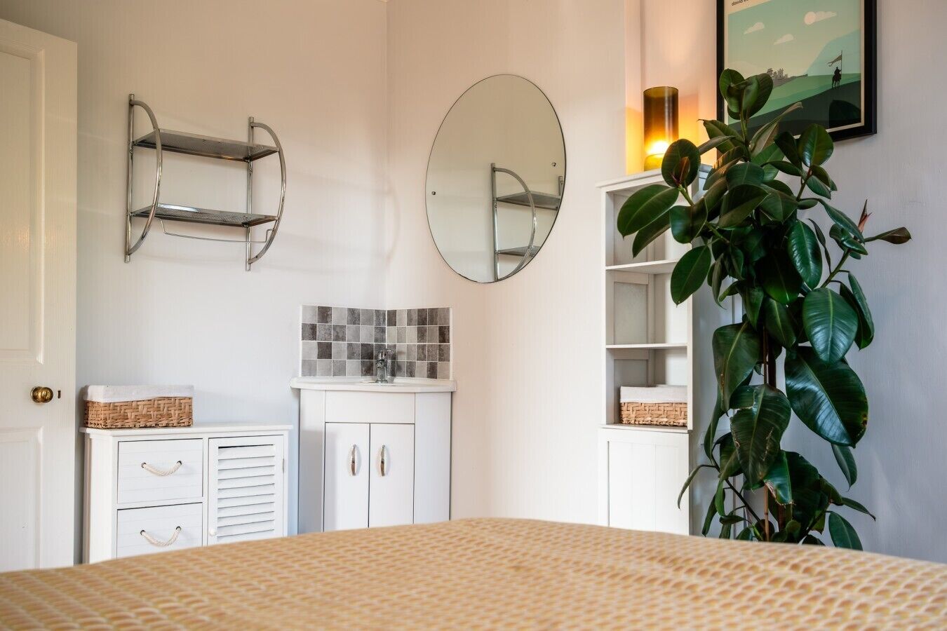 A bedroom with a bed, a dresser, a mirror, and a plant.