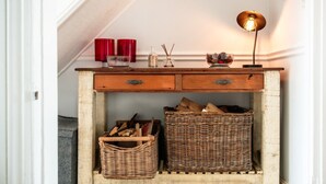 Ein Holzkonsolentisch mit zwei Schubladen, einer Lampe und zwei Korbwannen.