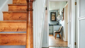 Eine Holztreppe führt zu einer Küche mit Fliesenboden und einem Stuhl.