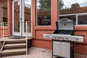 A patio with a barbecue grill, steps leading to a door, and a window with a view of a tree. - Historic & Modern, Two Hot Tubs, Great For Groups, Central Courtyard (Sedona)