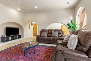 A living room with a brown leather sofa, a flat-screen TV, and a patterned rug. - Historic & Modern, Two Hot Tubs, Great For Groups, Central Courtyard (Sedona)