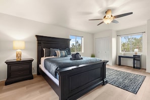 A bedroom with a large bed, a nightstand, a desk, a ceiling fan, and a view of the outdoors. - Historic & Modern, Two Hot Tubs, Great For Groups, Central Courtyard (Sedona)