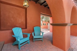 Two turquoise Adirondack chairs positioned on a brick patio adjacent to a building with orange walls and a wooden ceiling. - Historic & Modern, Two Hot Tubs, Great For Groups, Central Courtyard (Sedona)
