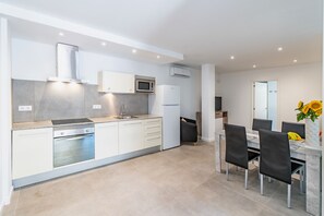A modern kitchen with white cabinetry, a built-in oven, a microwave, and a refrigerator. - Cabrera Apartment by Mallorca Infinity (Peguera)