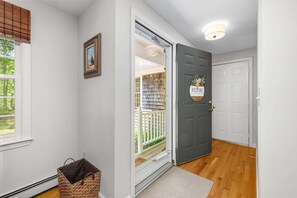 A hallway with a door, a basket, and a framed picture on the wall. - Sunset Pines Cape Cod retreat (East Sandwich)
