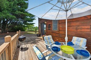 Ett trädäck med utemöbler, en grill och en skylt som visar var poolen finns.