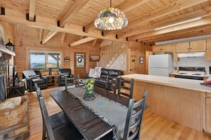 Ein Holzblockhaus Innenansicht mit Essbereich, Küche und einer Treppe.