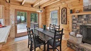 Un interior de madera con una mesa de comedor, sillas, una chimenea y una puerta que da al exterior.