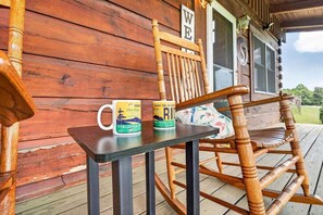 Una mecedora de madera y una mesa con dos tazas en un porche.