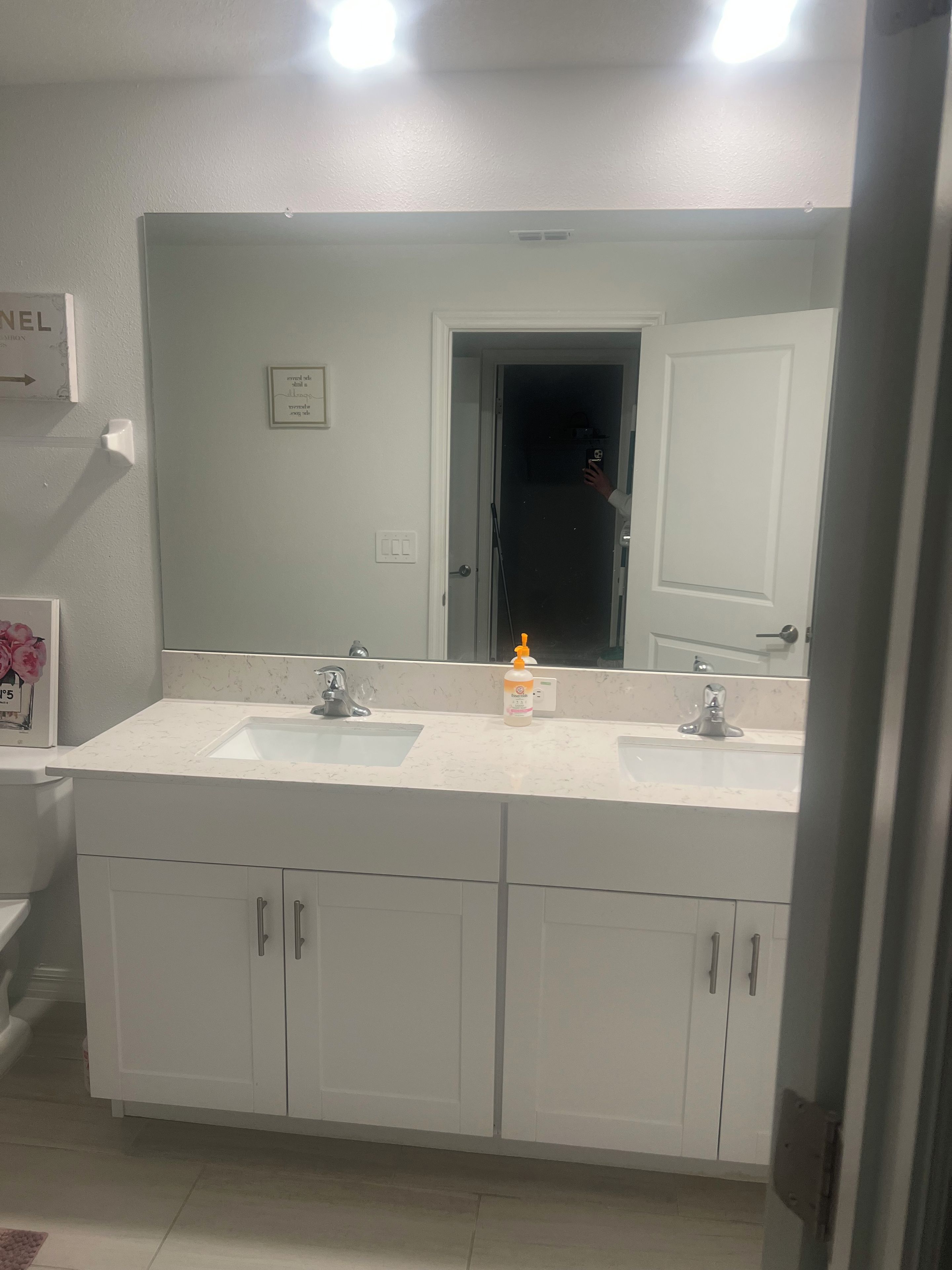 A bathroom with two sinks, a large mirror, and white cabinets.