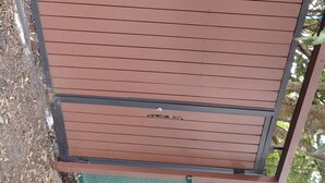 Una reja metálica marrón con una cerca de alambre detrás.