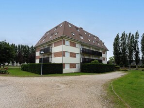 Ein mehrgeschossiges Wohngebäude mit Backsteinfassade, mehreren Balkonen und einer Schotterauffahrt.