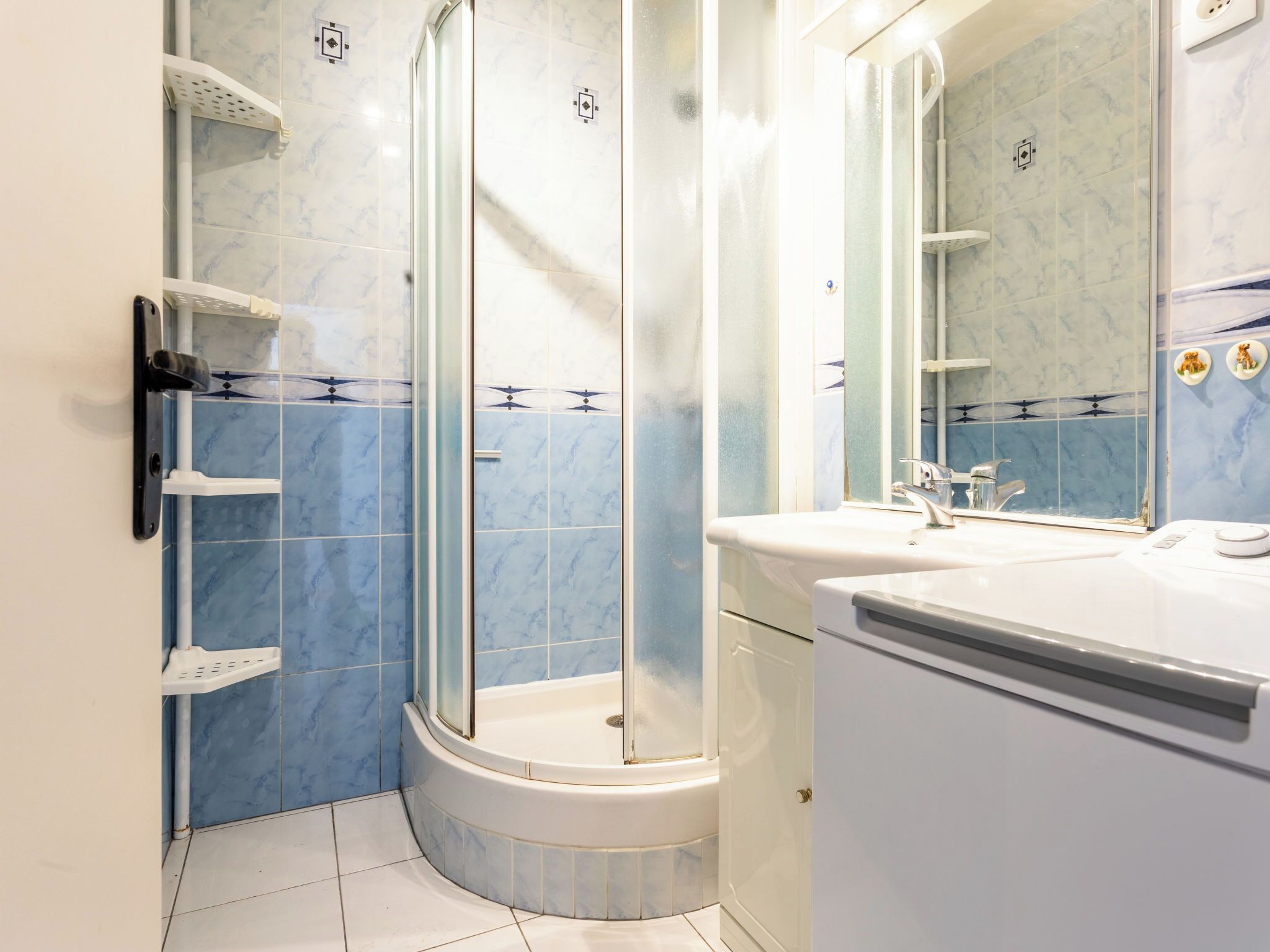 A modern bathroom with a glass-enclosed shower, a white sink, and a mirror above it.