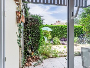 Ein Garten mit einem grünen Stuhl, einem Fahrrad und einer Hecke.