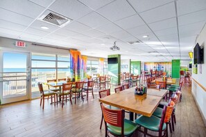 Ein Restaurant mit mehreren Tischen und Stühlen, einem Ausgangsschild und Blick durch große Fenster.