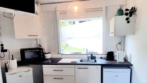 Una cocina compacta con microondas, lavamanos y un refrigerador pequeño.